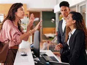 shutterstock_2542553393_frustrated woman at reception_aizkaitināta sieviete reģistratūrā.jpg