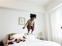 Shutterstock_758272753_kid jumping on bed_bērns lēkā uz gultas.jpg