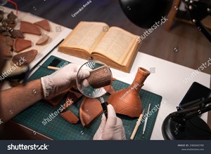 WIKI_20252107_stock-photo-close-up-of-an-archaeologist-working-late-in-the-office-studying-an-artifact-of-an-ancient-culture-2365642765.jpg